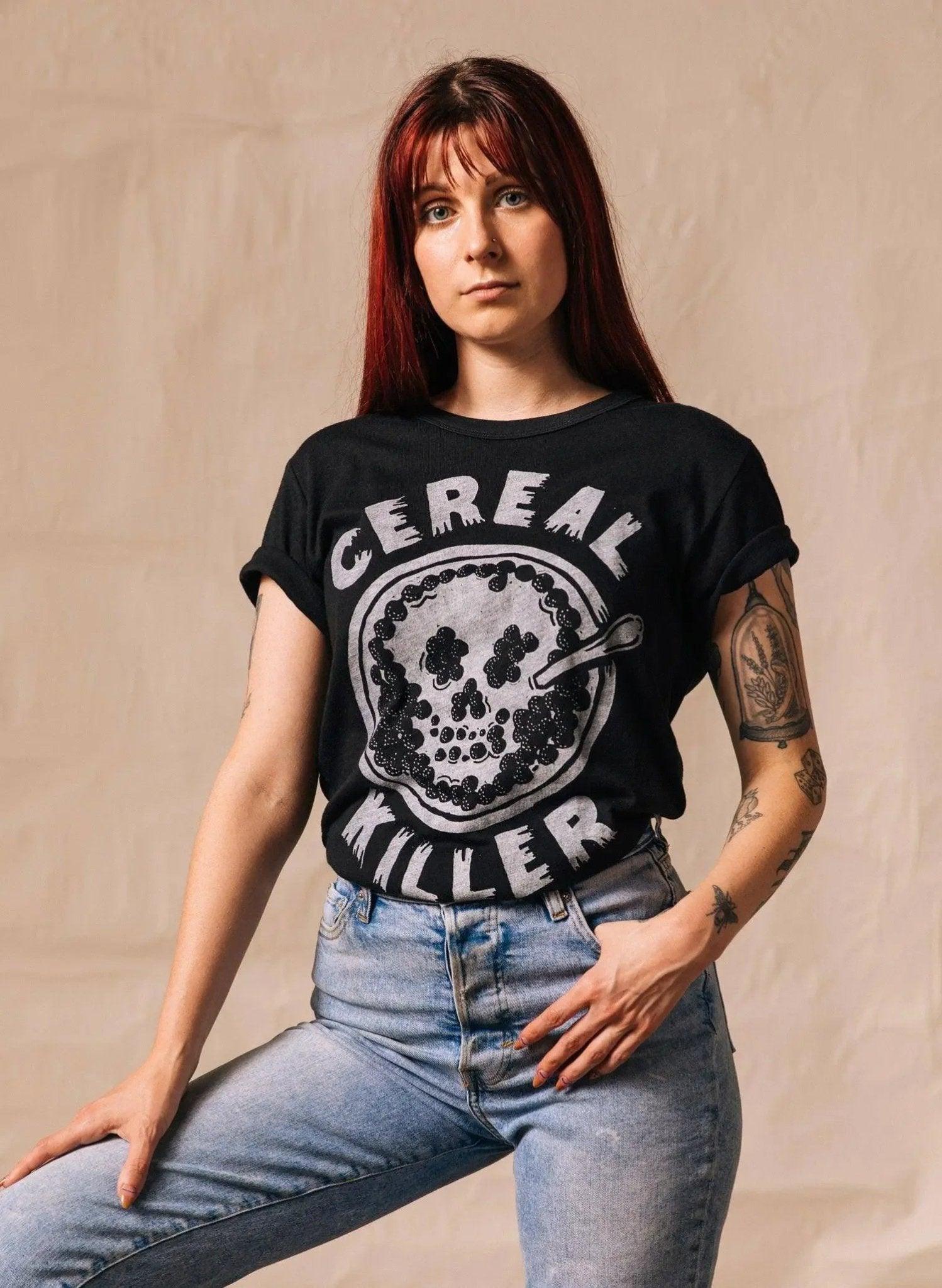 Woman wearing black 'Cereal Killer' graphic tee with skull design, paired with high-waisted jeans, edgy fashion style