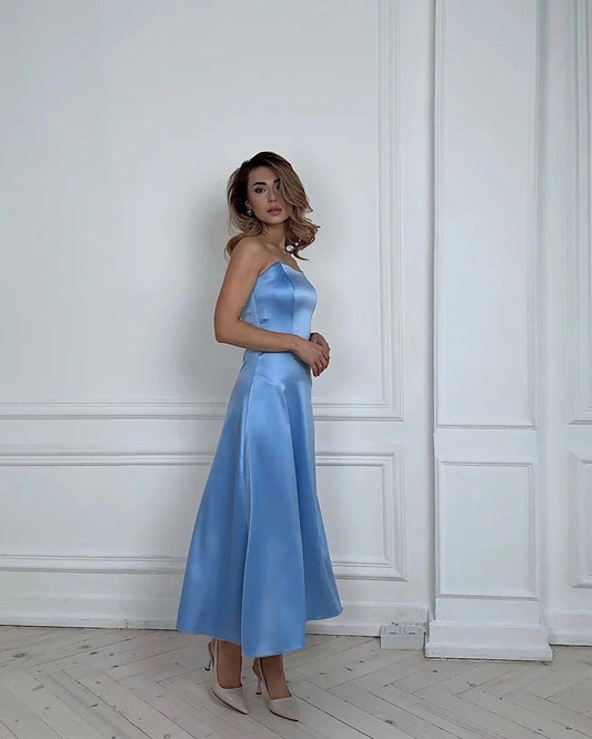 Woman in elegant light blue satin strapless midi dress, perfect for evening events and fashion occasions