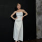 Woman in elegant white strapless midi dress with black strappy heels, perfect for fashion events