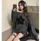 Woman in off-shoulder star print top, black boots, and headphones taking mirror selfie