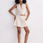 Woman in cream sleeveless blazer vest and matching pleated mini skirt, stylish summer fashion set