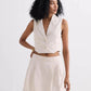 Woman in cream sleeveless blazer vest and pleated mini skirt, stylish summer fashion set