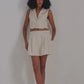 Woman in cream sleeveless cropped blazer and matching pleated shorts, modern fashion set