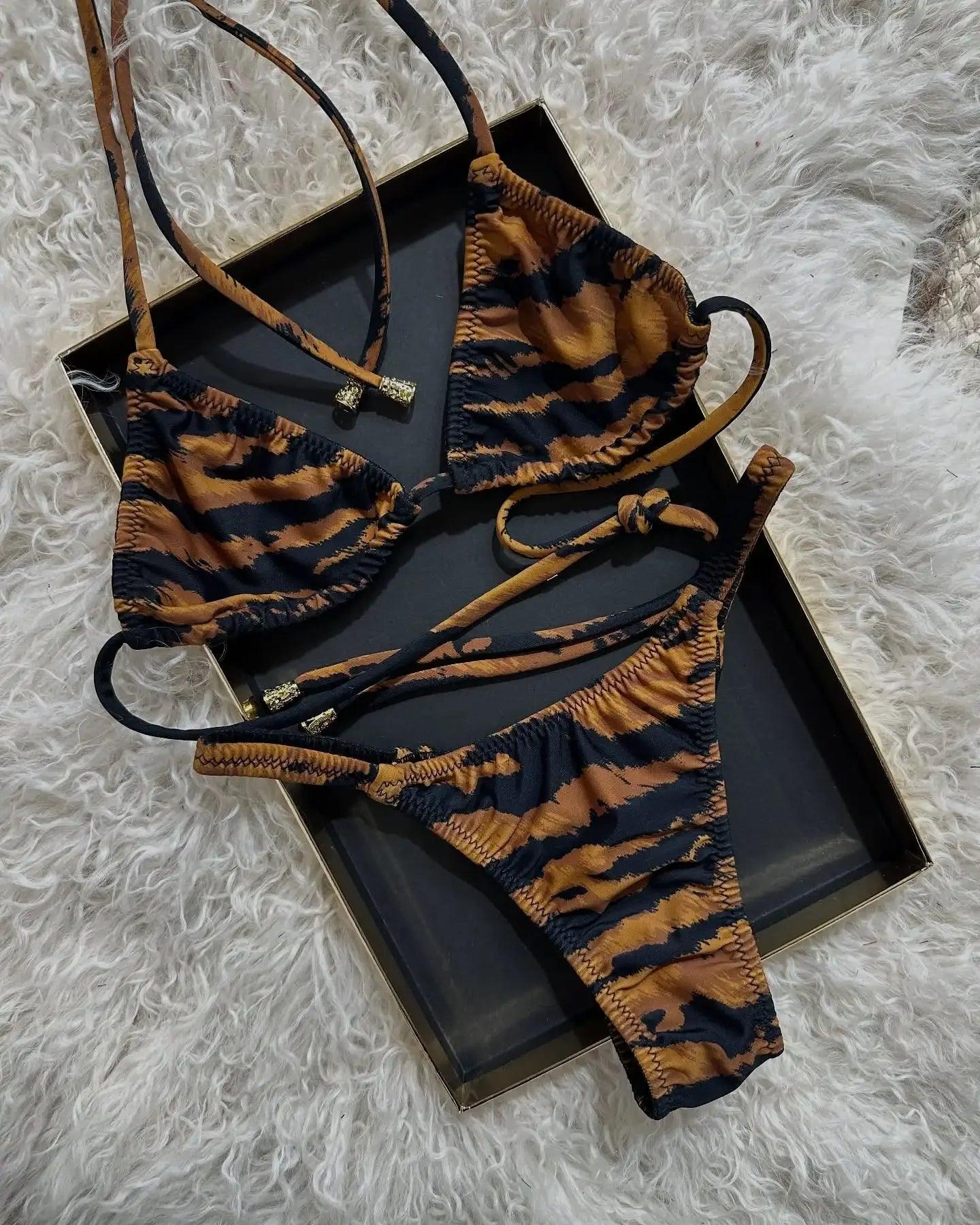 Tiger print bikini set with adjustable straps, displayed on black tray over fluffy white rug