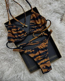 Tiger print bikini set with adjustable straps, displayed on black tray over fluffy white rug