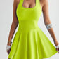 Bright lime green women's tennis dress with flared skirt, sleeveless design, and sporty wristbands