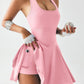 Pink women's athletic romper with flared skirt, holding baseball, sporty fashion outfit