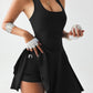 Woman in black athletic tank top and skort holding baseball, fitness fashion outfit