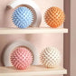 Spiky massage balls in pastel blue, orange, pink, white on wooden shelves for fitness and relaxation