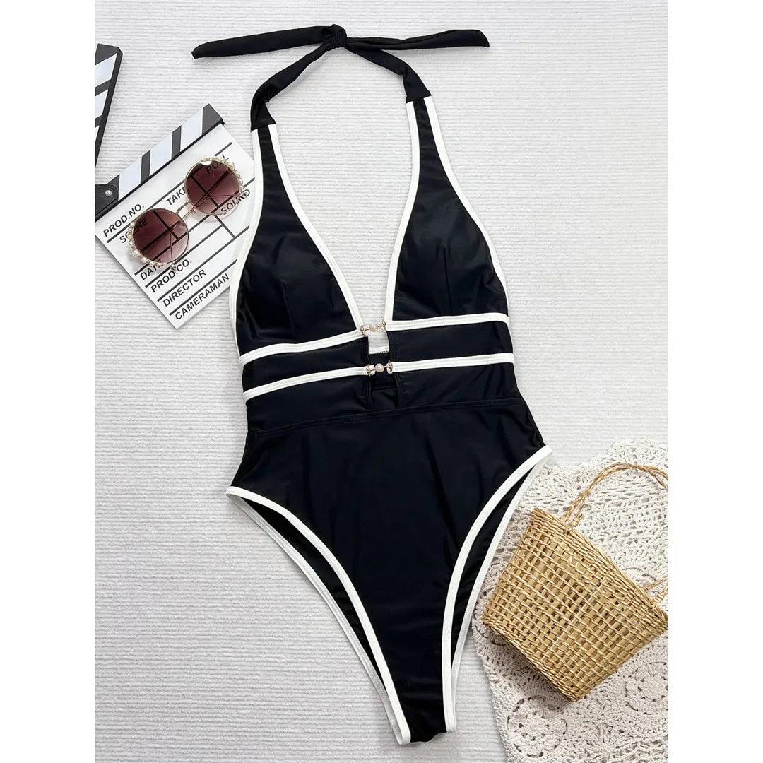 Black and white one-piece swimsuit with halter neck and side cutouts, styled with sunglasses and straw bag