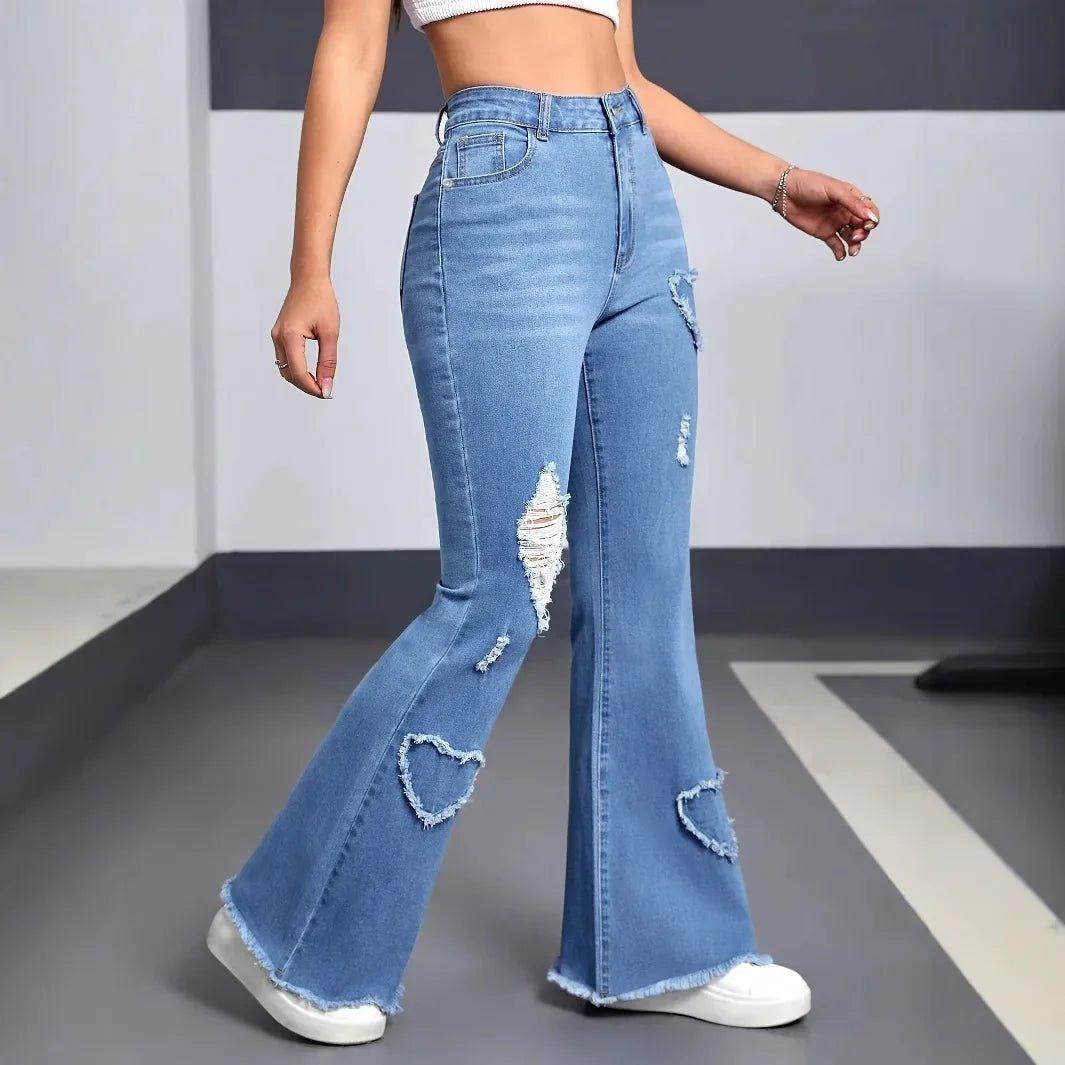 Women's high-waisted ripped flare jeans with heart cutouts, paired with white sneakers for casual fashion.