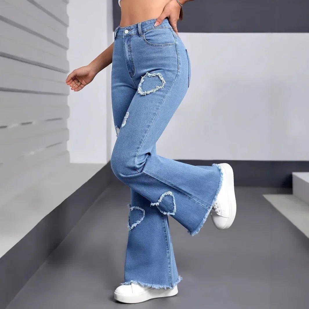 Women's high-waisted ripped flare jeans with heart cutouts, paired with white sneakers for casual fashion