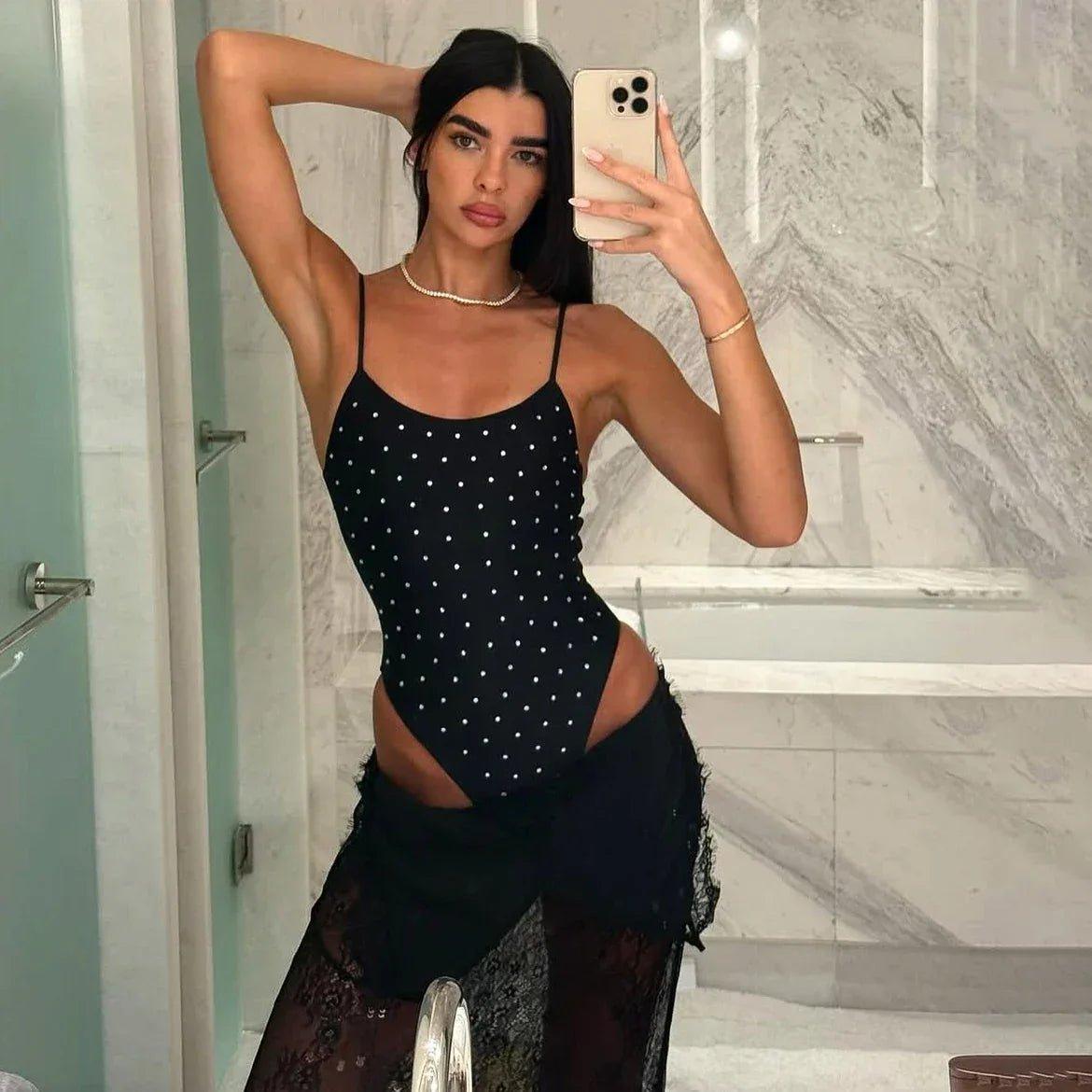 Woman in black polka dot bodysuit with lace skirt, taking mirror selfie in bathroom