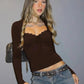 Woman in brown scalloped crop top with long sleeves, paired with blue jeans and studded belt, fashion look