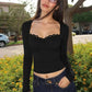 Woman in black long sleeve crop top with lace trim and bow, styled with jeans outdoors