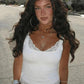Woman in white lace trim tank top, hoop earrings, and layered necklaces, outdoor street style fashion