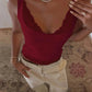 Woman wearing burgundy lace trim tank top with beige pants, styled with necklace and rings for casual fashion