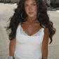 Woman in white lace trim tank top, hoop earrings, layered necklaces, outdoor street style fashion