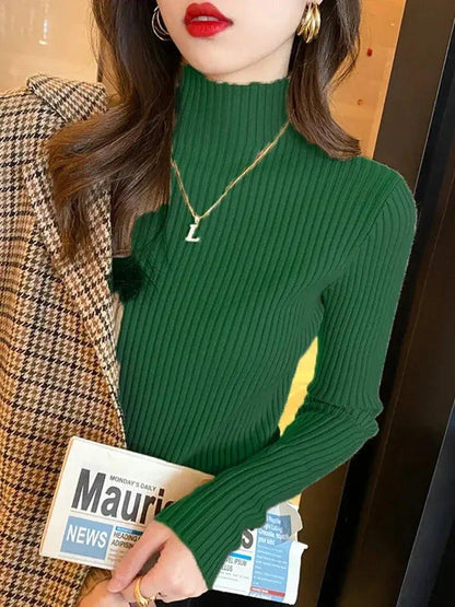 Woman in green ribbed turtleneck sweater with plaid blazer, gold jewelry, and red lipstick