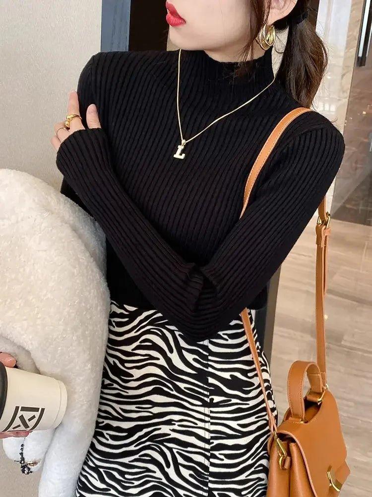 Woman in black ribbed turtleneck and zebra print skirt with gold accessories