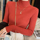 Woman wearing red ribbed turtleneck sweater, gold necklace, and white pleated skirt for fashion look