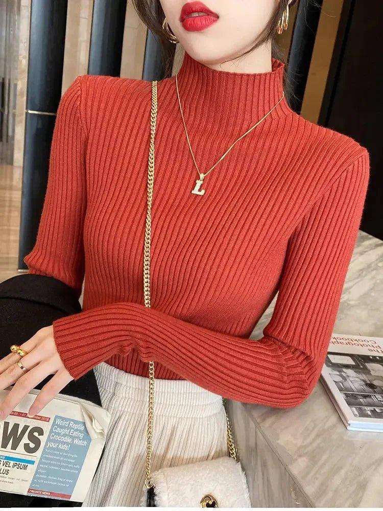 Woman wearing red ribbed turtleneck sweater, gold necklace, and white pleated skirt for fashion look