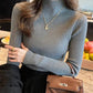 Woman in gray ribbed turtleneck sweater, gold necklace, and brown croc-texture handbag, stylish fashion look