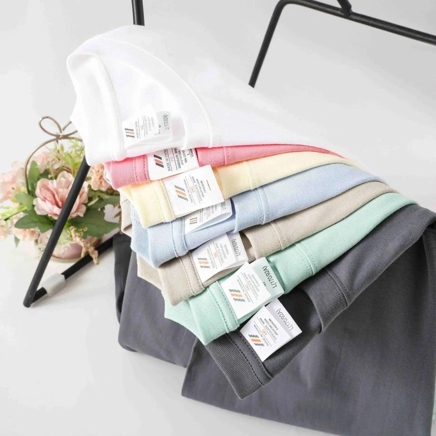 Stack of pastel and neutral women's fashion t-shirts with tags, soft cotton tops for casual wear