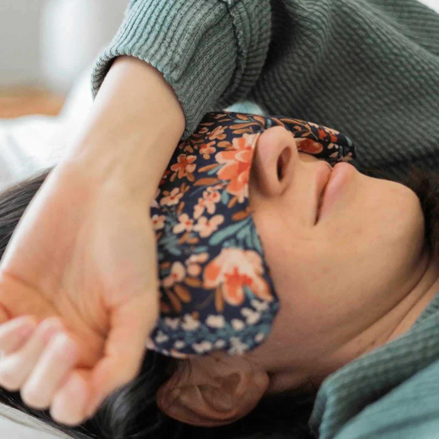 Woman wearing floral sleep mask, relaxing in cozy green sweater for beauty and fashion comfort