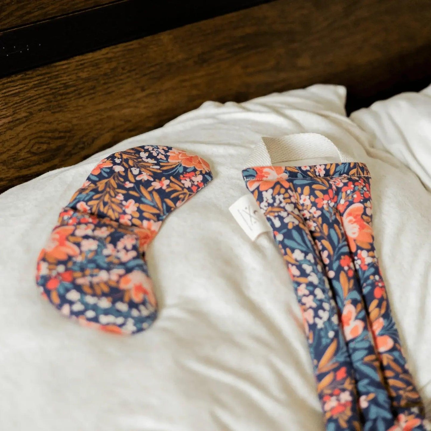 Floral print sleep mask and matching eye pillow on white bedding for women's fashion and relaxation