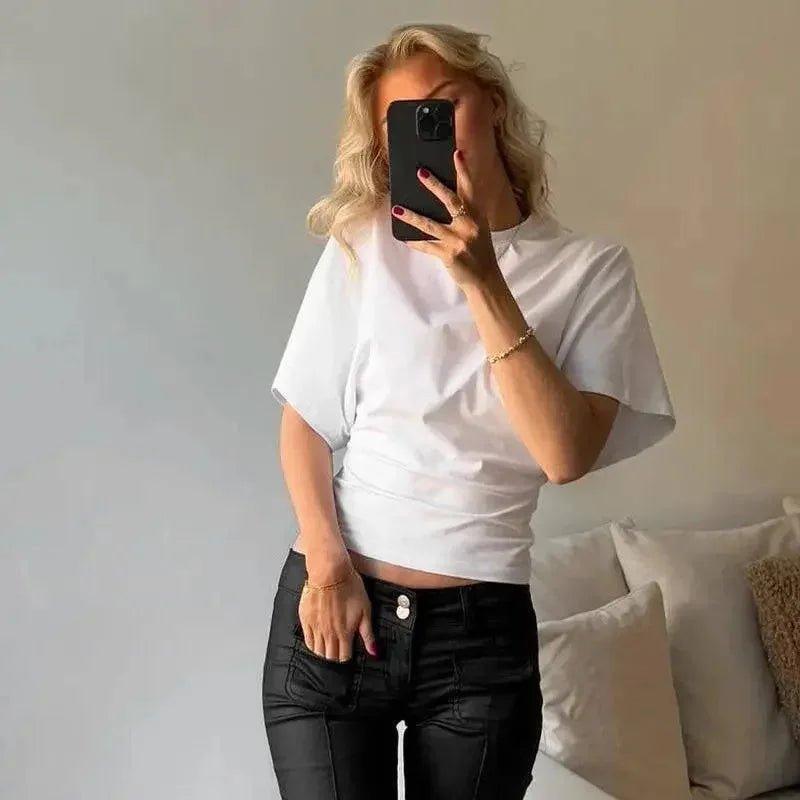 Woman in white crop top and black jeans taking mirror selfie, casual fashion outfit