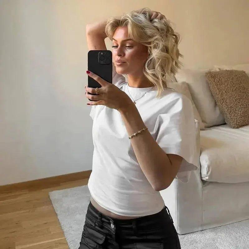 Woman taking selfie in white t-shirt and black pants, casual fashion outfit