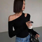 Woman in black one-shoulder top and blue jeans holding coffee, stylish fashion outfit