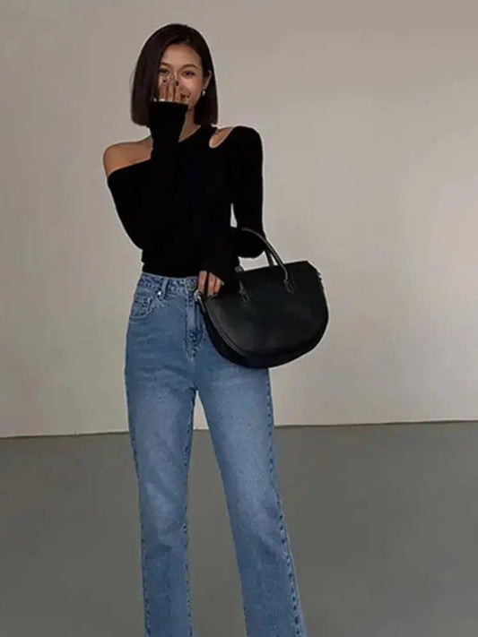 Woman in black off-shoulder top, blue jeans, and black handbag — stylish fashion outfit
