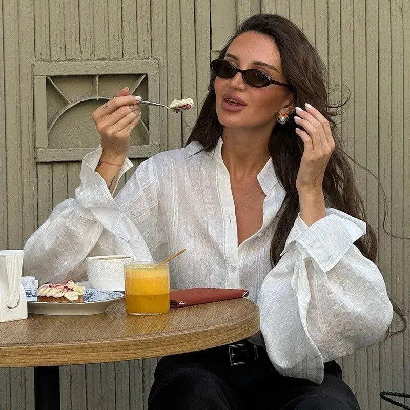 Woman in white blouse eating dessert at café, fashion style