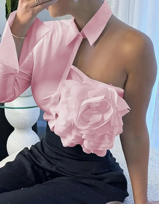 Woman in pink satin one-shoulder top with floral rose detail, paired with black embellished pants