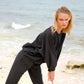 Woman in black oversized sweatshirt and joggers at beach, casual fashion
