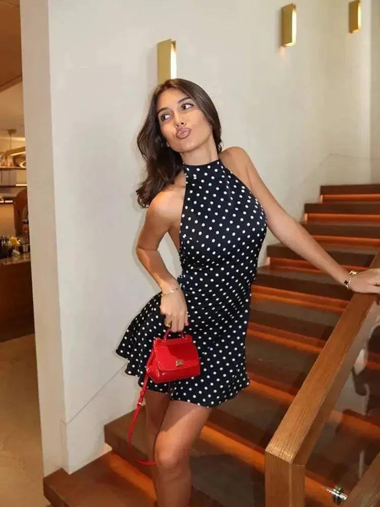 Woman in polka dot dress with red handbag on staircase