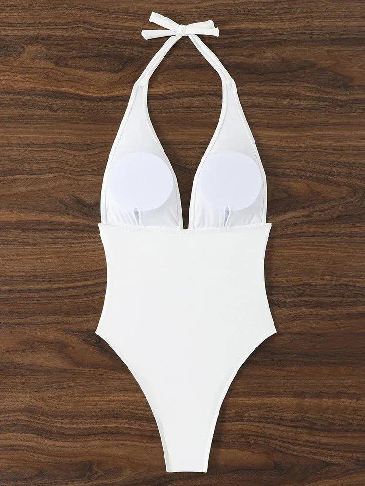 White halter neck one-piece swimsuit with tie back, laid flat on wood background