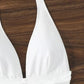 White halter neck swimsuit top with ruched detail on wooden background
