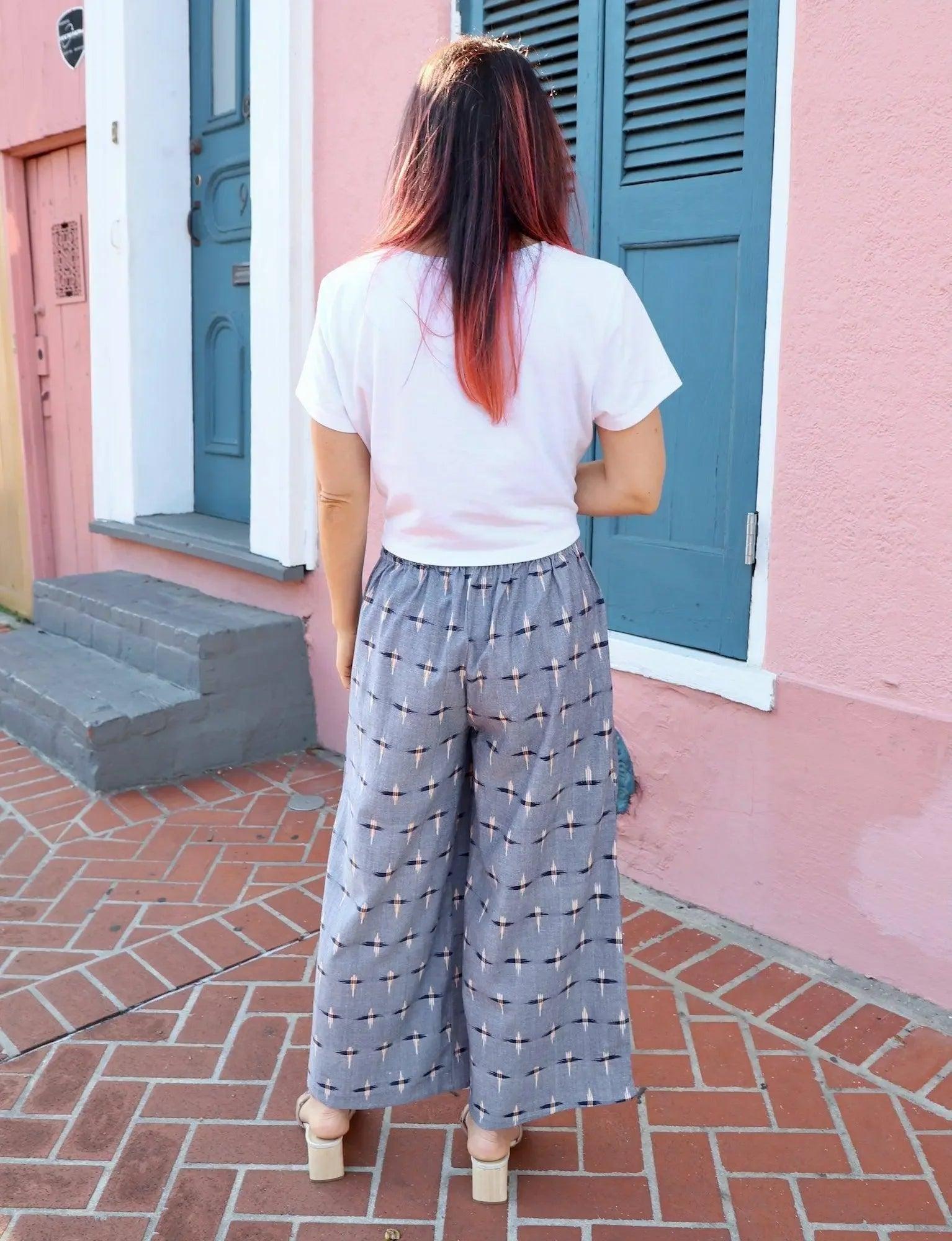 Woman in white tee and patterned wide-leg pants, pink building backdrop, fashion outfit