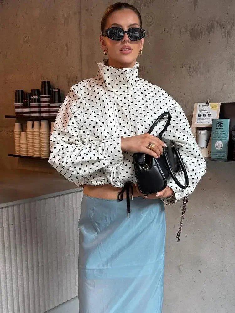 Woman in polka dot crop top and blue skirt with black handbag, stylish fashion outfit