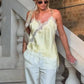 Woman in lace-trimmed satin camisole and white pants, stylish summer outfit