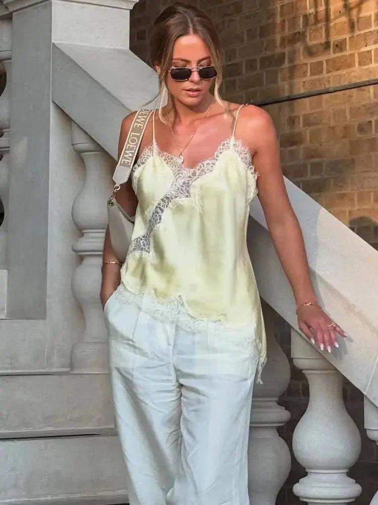 Woman in lace-trimmed satin camisole and white pants, stylish summer outfit