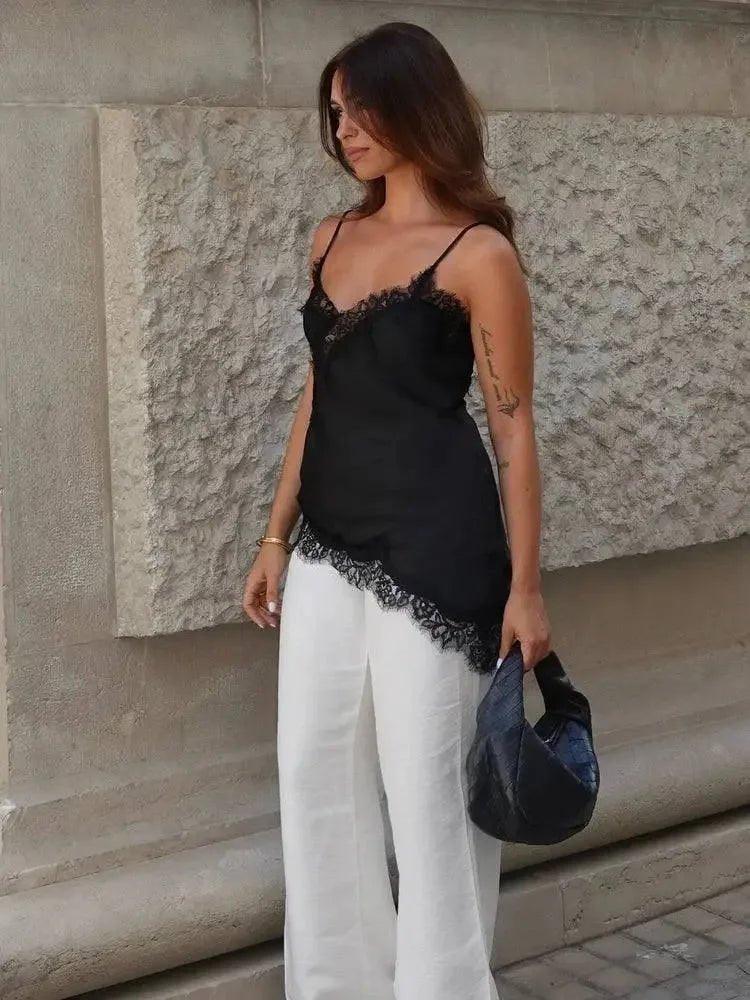 Woman in black lace camisole top and white wide-leg pants, holding black handbag, street style fashion