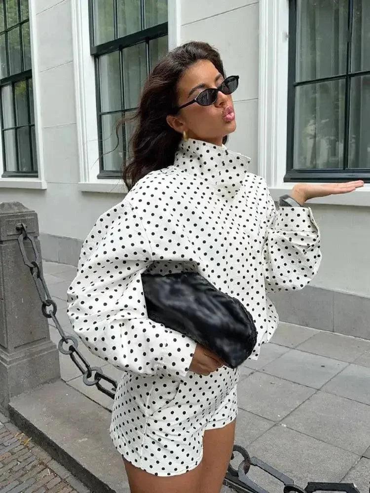 Woman in white polka dot fashion set with black clutch and sunglasses, street style