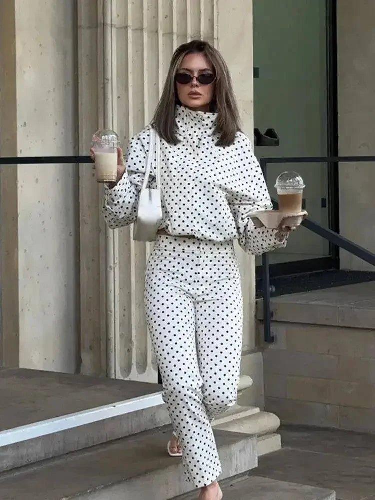 Woman in white polka dot fashion set holding coffee, stylish streetwear outfit