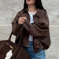 Woman in brown oversized jacket, blue jeans, and yellow sunglasses carrying matching tote bag