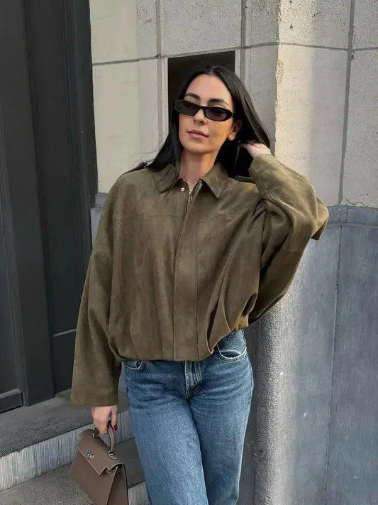 Woman in olive suede shirt, jeans, sunglasses, and handbag — chic street style fashion