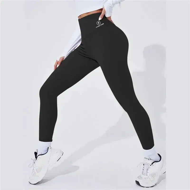 Black high-waisted workout leggings with logo, paired with white sneakers for women's fitness fashion
